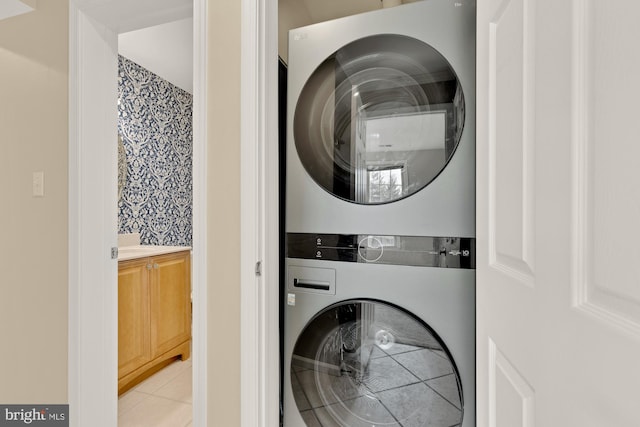 laundry area featuring light tile patterned floors, stacked washer and dryer, and laundry area