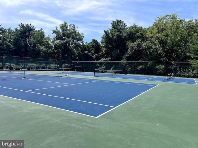 view of tennis court with community basketball court and fence