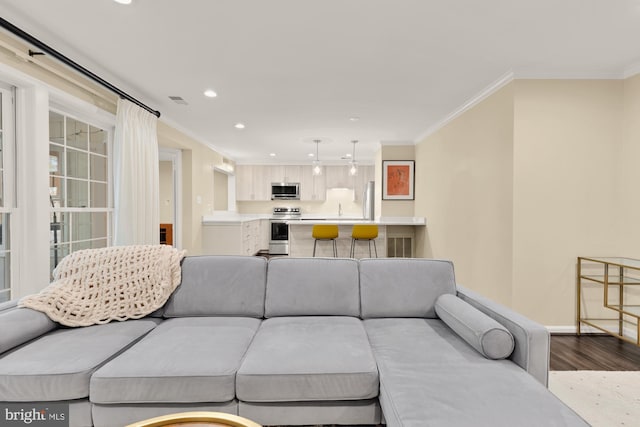 living area featuring visible vents, crown molding, baseboards, dark wood finished floors, and recessed lighting