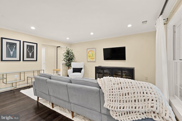 living area with dark wood-type flooring, crown molding, and recessed lighting