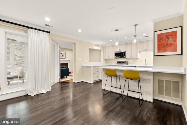 kitchen featuring visible vents, a breakfast bar area, light countertops, appliances with stainless steel finishes, and a peninsula