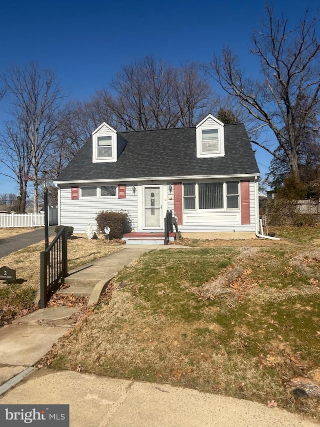 view of front facade with a shingled roof and fence