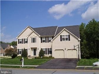 colonial inspired home with driveway and an attached garage