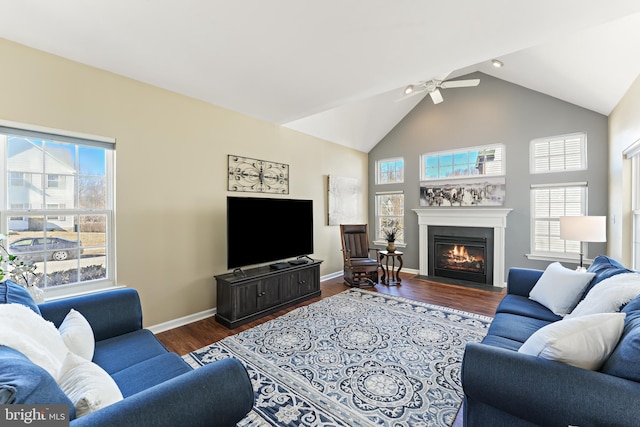 living area with baseboards, a fireplace with flush hearth, ceiling fan, dark wood-style flooring, and high vaulted ceiling