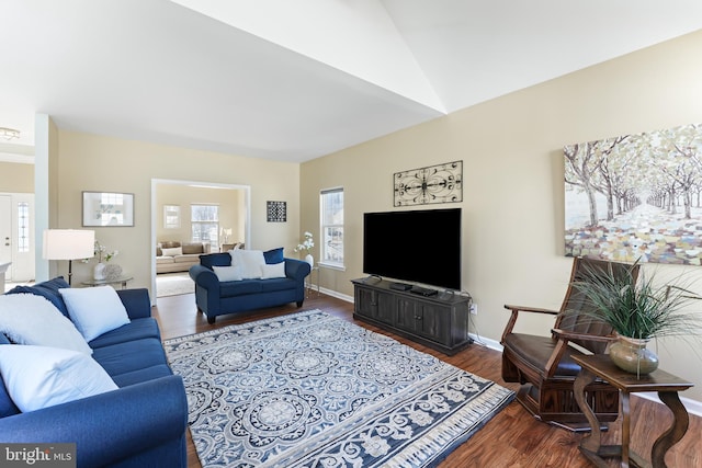 living area featuring lofted ceiling, baseboards, and wood finished floors