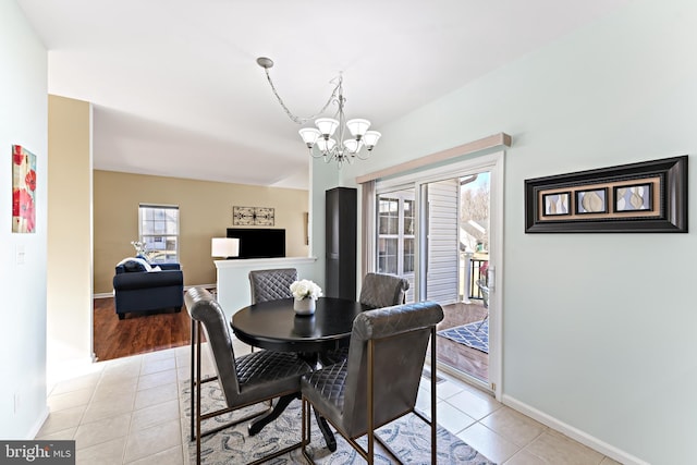 dining space with light tile patterned flooring, a notable chandelier, and baseboards