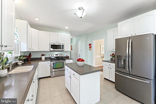 kitchen with stainless steel appliances, dark countertops, a sink, and light tile patterned flooring