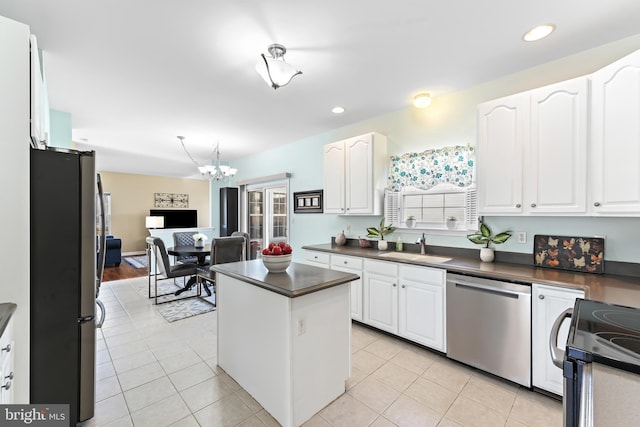 kitchen with stainless steel appliances, dark countertops, a sink, and white cabinetry