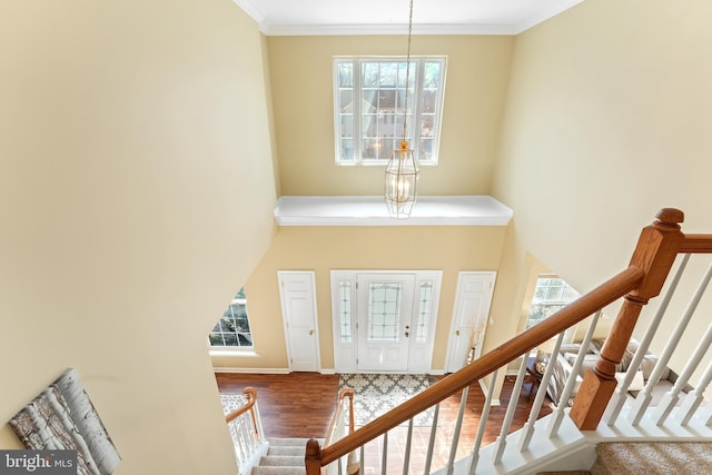 entryway with a towering ceiling, crown molding, stairs, and wood finished floors