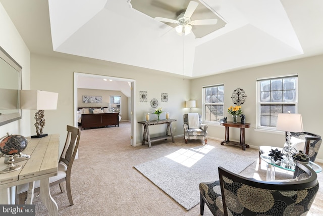 interior space with a ceiling fan, a tray ceiling, lofted ceiling, and baseboards