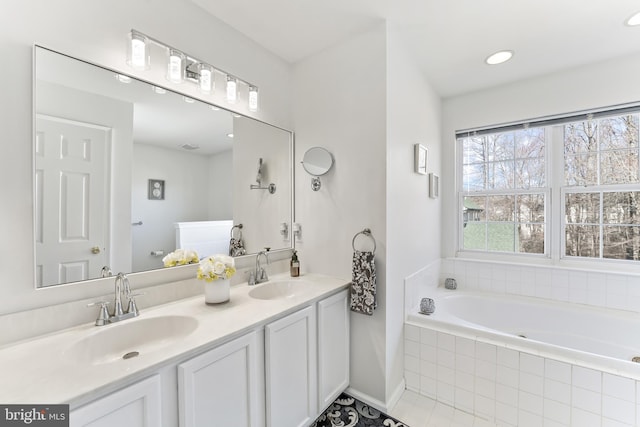 bathroom with recessed lighting, double vanity, a sink, and a bath