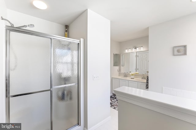 bathroom with a stall shower, a sink, and double vanity