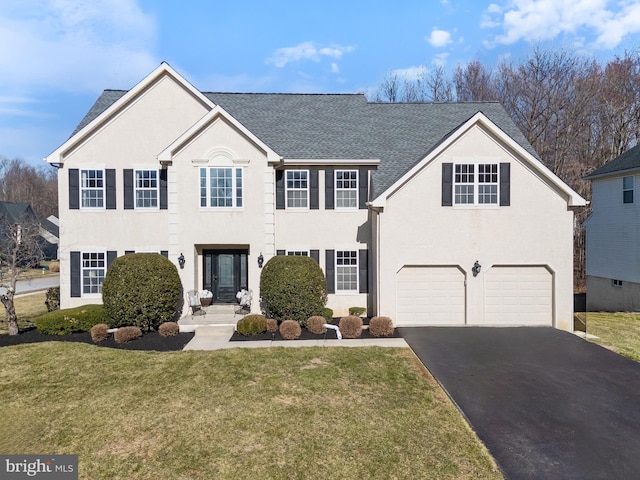 colonial inspired home with driveway, an attached garage, roof with shingles, and a front yard