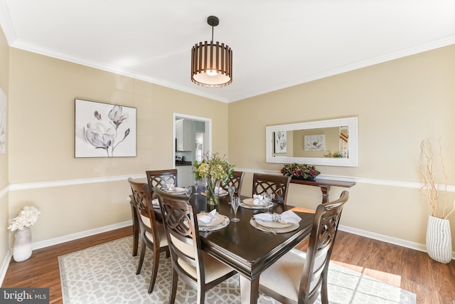 dining room featuring crown molding, baseboards, and wood finished floors