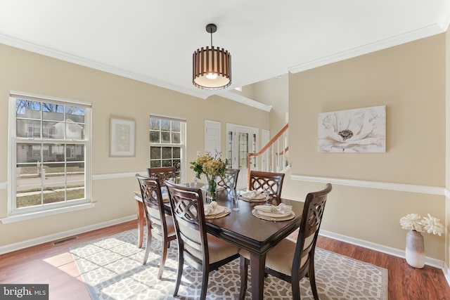 dining room featuring baseboards, crown molding, visible vents, and wood finished floors