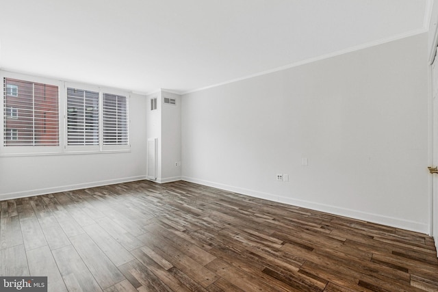 unfurnished room with dark wood-style floors, ornamental molding, visible vents, and baseboards