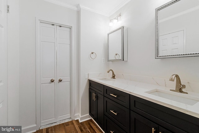 bathroom featuring double vanity, wood finished floors, a sink, and crown molding