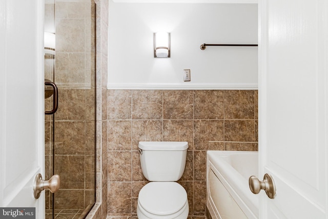 full bath with a stall shower, toilet, and tile walls