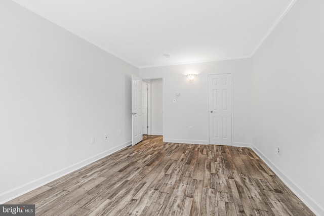 unfurnished room with ornamental molding, baseboards, and wood finished floors