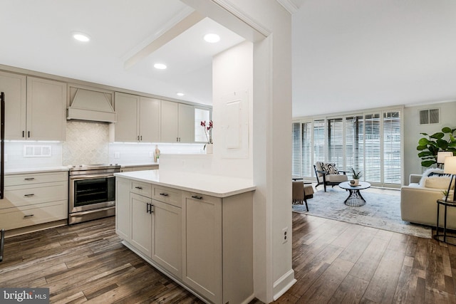 kitchen with visible vents, dark wood-type flooring, light countertops, stainless steel range with electric stovetop, and premium range hood