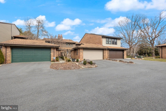 view of front facade featuring brick siding, aphalt driveway, and a garage