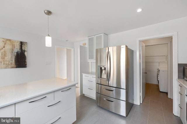 kitchen featuring glass insert cabinets, light countertops, stainless steel refrigerator with ice dispenser, white cabinets, and modern cabinets