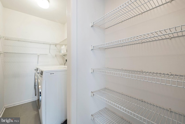 clothes washing area featuring tile patterned flooring, laundry area, baseboards, and separate washer and dryer