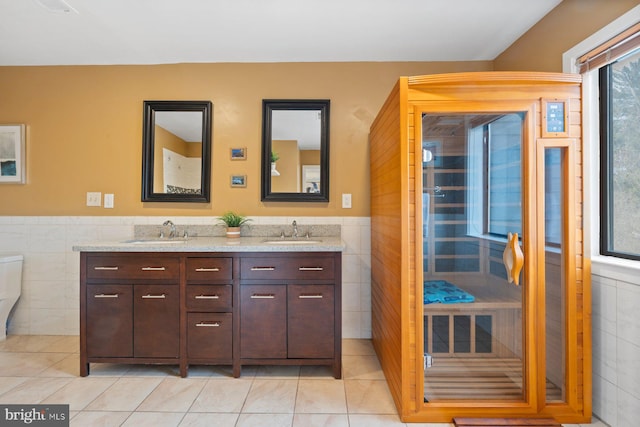 full bathroom featuring tile walls, double vanity, a sauna, and a sink