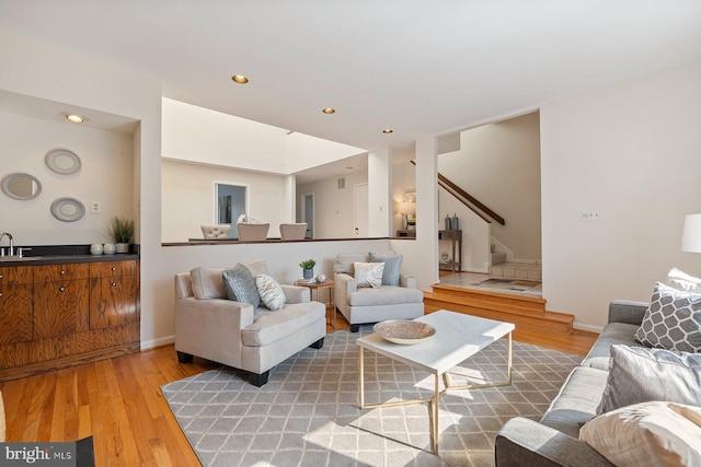 living area featuring recessed lighting, stairway, baseboards, and light wood-style floors