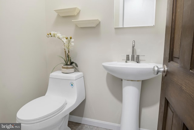 half bath featuring baseboards and toilet