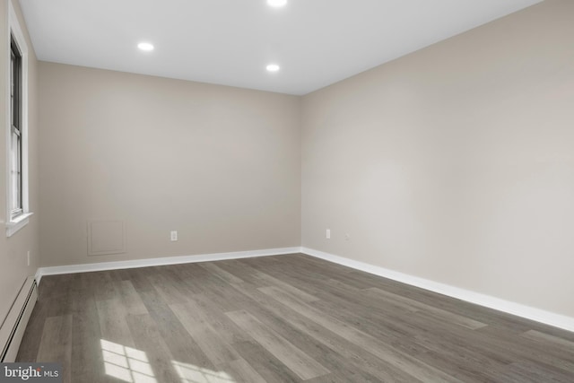 empty room featuring recessed lighting, baseboards, baseboard heating, and wood finished floors