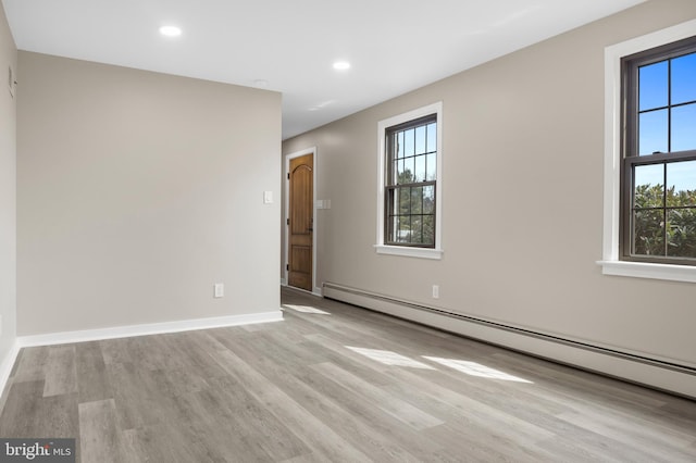 unfurnished room with a baseboard heating unit, recessed lighting, baseboards, and wood finished floors