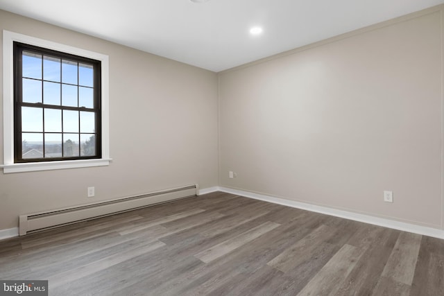 unfurnished room with baseboards, baseboard heating, and wood finished floors