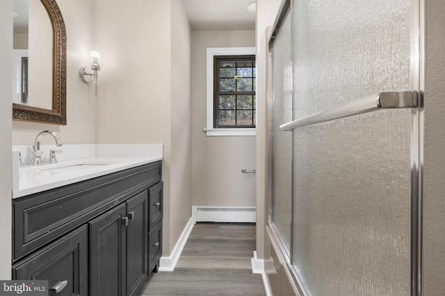 bathroom with baseboards, vanity, baseboard heating, and wood finished floors