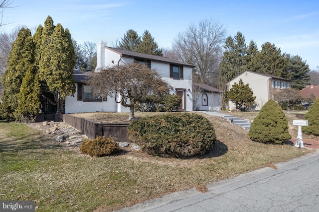 view of front of property featuring a front lawn, a chimney, and stucco siding