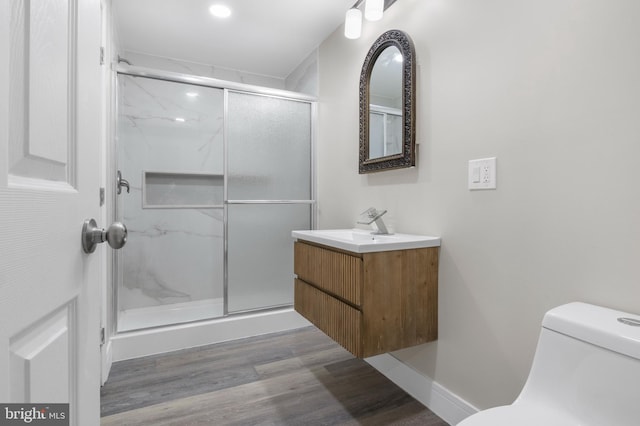 full bath featuring toilet, a marble finish shower, wood finished floors, and vanity