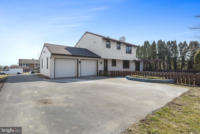 view of front of property featuring driveway, a chimney, an attached garage, and fence