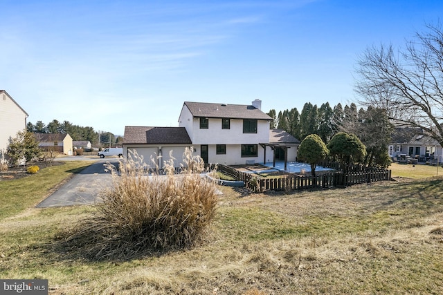 back of house with a garage, a yard, a chimney, and fence