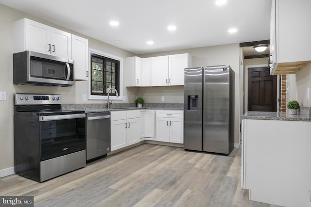 kitchen with appliances with stainless steel finishes, light wood-type flooring, and white cabinetry