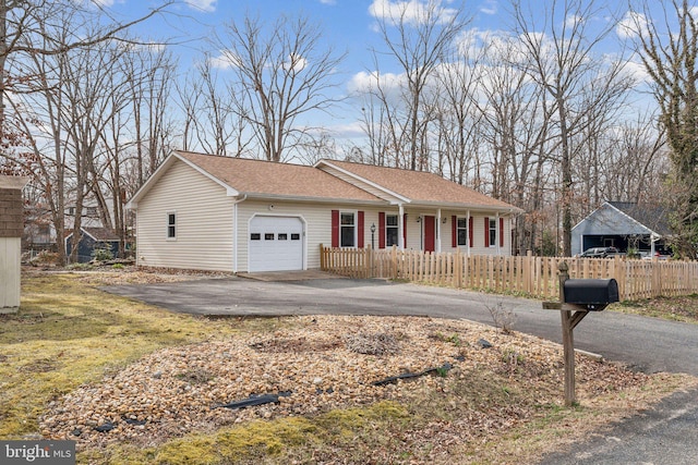 single story home with roof with shingles, an attached garage, covered porch, a fenced front yard, and aphalt driveway