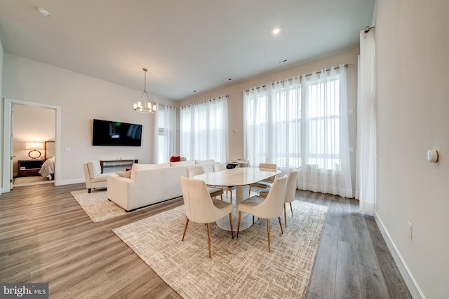 dining space with baseboards, wood finished floors, and an inviting chandelier