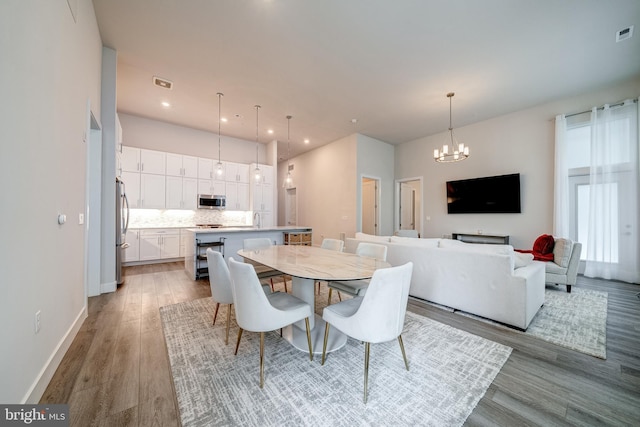 dining area featuring recessed lighting, a notable chandelier, visible vents, baseboards, and light wood-style floors