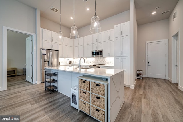 kitchen featuring stainless steel appliances, visible vents, decorative backsplash, white cabinetry, and a sink