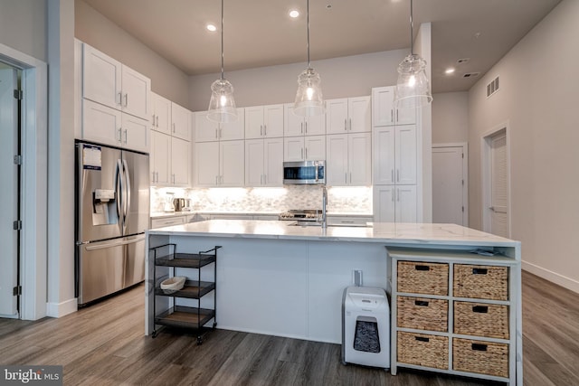 kitchen featuring visible vents, backsplash, appliances with stainless steel finishes, white cabinetry, and wood finished floors