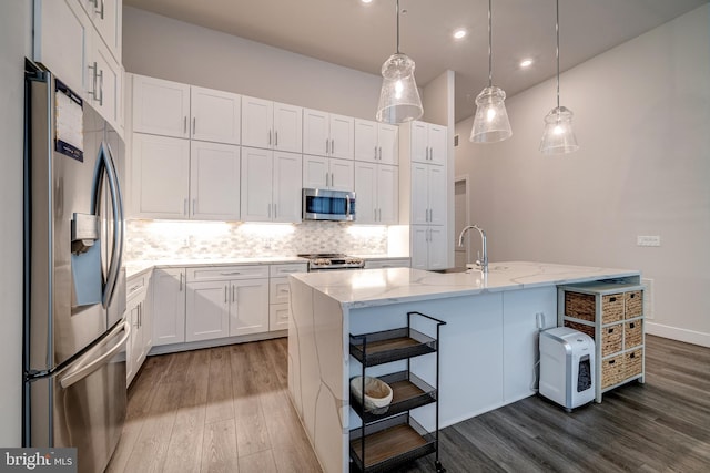 kitchen with appliances with stainless steel finishes, white cabinets, dark wood finished floors, and backsplash