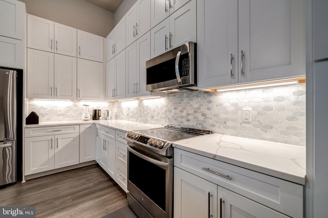 kitchen with white cabinetry, stainless steel appliances, and backsplash