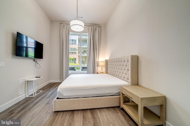 bedroom with visible vents, baseboards, and wood finished floors