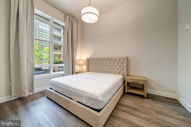 bedroom with multiple windows, baseboards, and wood finished floors