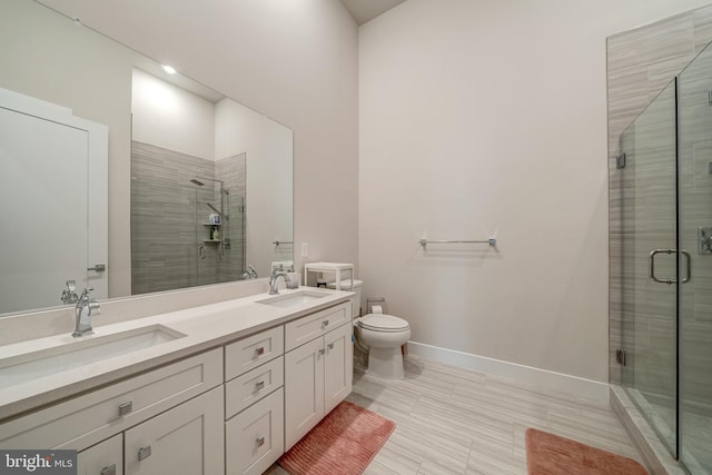 full bathroom with double vanity, a stall shower, a sink, and baseboards