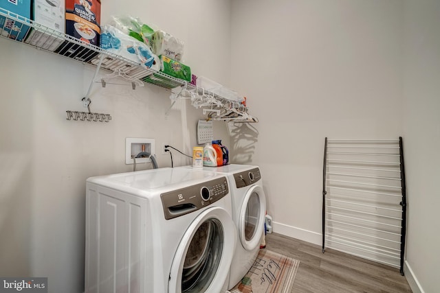 washroom with laundry area, washing machine and dryer, baseboards, and wood finished floors